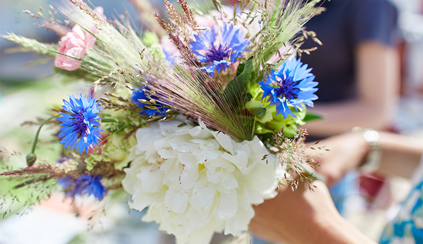 A woman holding bouquet of wildflowers outdoors